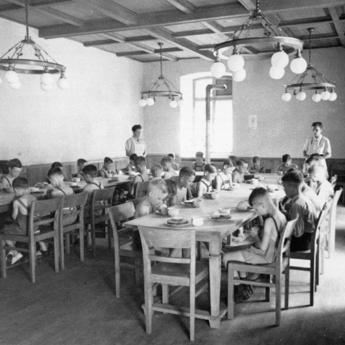 Kinder sitzen beim Essen in einem Saal