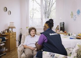 Pflegerin und alte Frau sitzen zusammen und sprechen