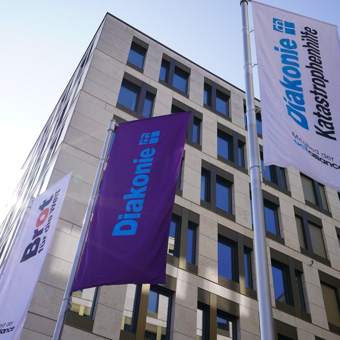 Fahnen der drei Marken Diakonie Deutschland, Brot für die Welt und Diakonie Katastrophenhilfe vor dem Gebäude des Evangelischen Werks für Diakonie und Entwicklung