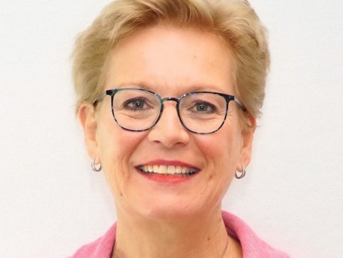Eine Frau mit Brille schaut lächelnd in die Kamera. 