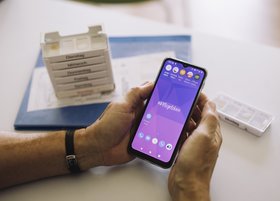 Hände einer älteren Person halten ein Smartphone 