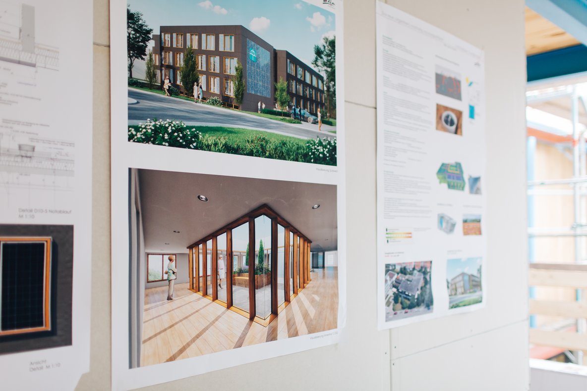 An der Wand aufgehängte Pläne und Visualisierung eines energetischen Gebäudes