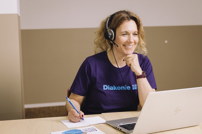 Eine Pflegerin lächelt in die Kamera ihres Laptops