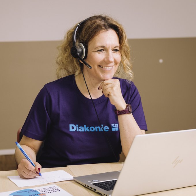 Eine Pflegerin lächelt in die Kamera ihres Laptops