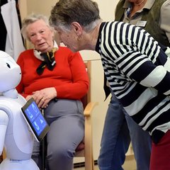 Eine Seniorin spricht mit Roboter Emma
