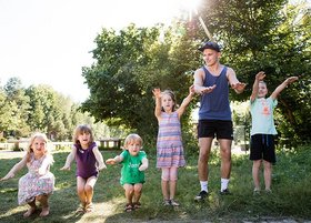 Kinder und ein junger Erwachsener machen eine Welle