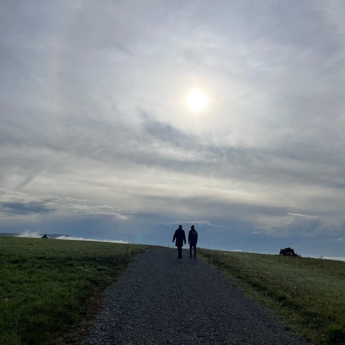 Zwei Männer von hinten beim Spaziergang auf einem Hügel