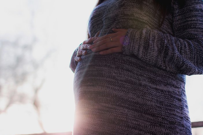 Bauch einer schwangeren Frau im Pullover
