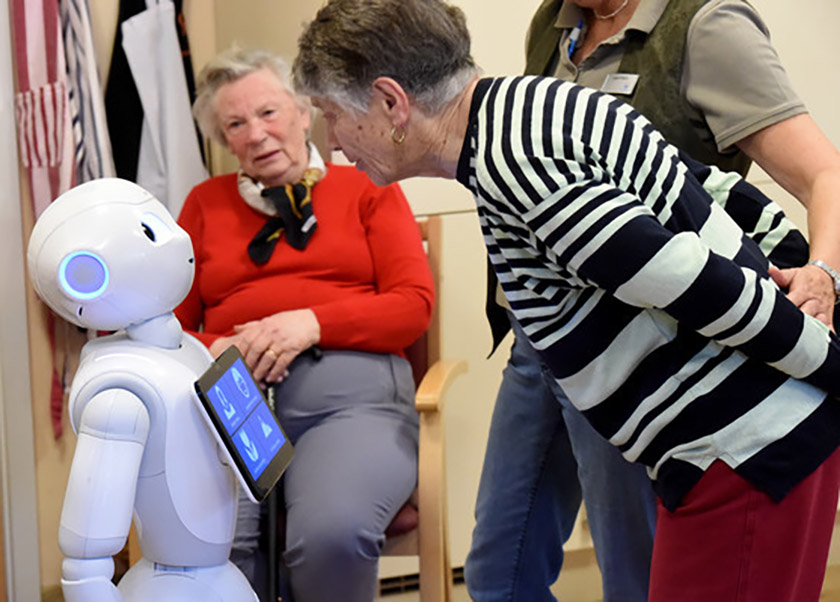 Eine Seniorin spricht mit Roboter Emma