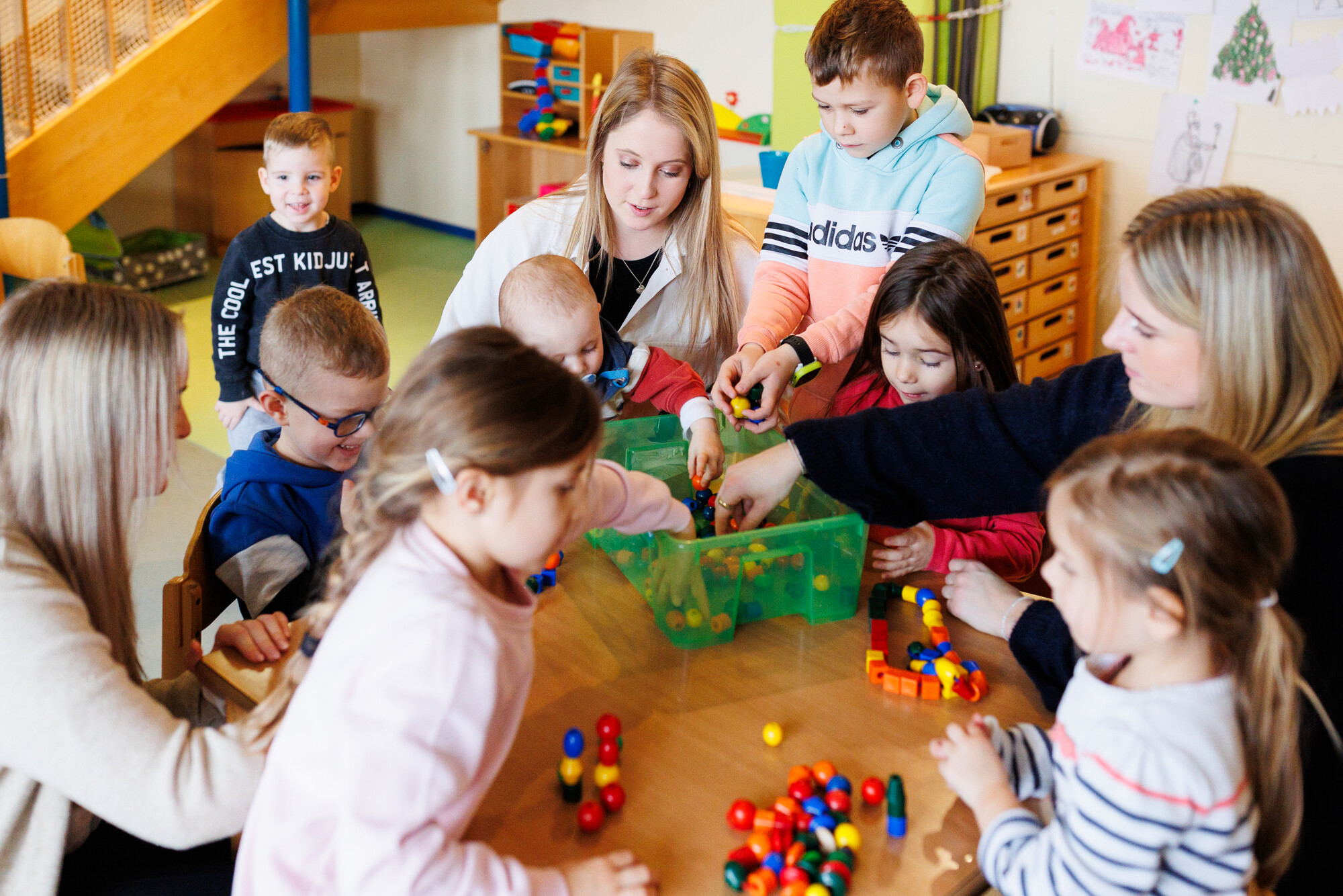 Kinder und Frauen sitzen um einen Tisch herum und spielen