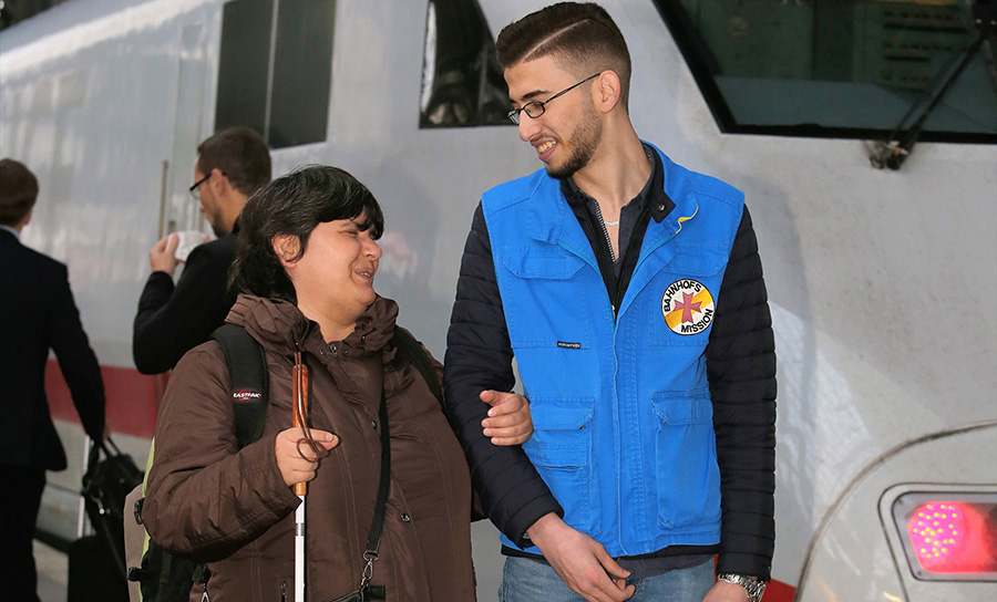 Ein Mann von der Bahnhofsmission begleitet eine blinde Frau